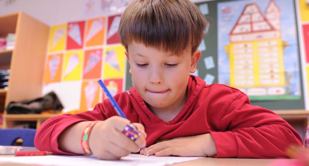 Ein Junge schreibt auf einem Blatt Papier.